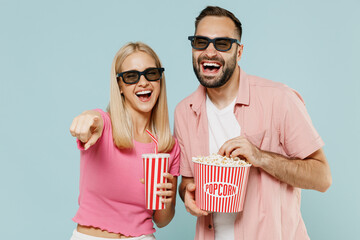 Obraz premium Young couple family man woman friends in 3d glasses watch movie film hold bucket of popcorn cup of soda pop laugh isolated on plain blue background studio People emotion in cinema lifestyle concept