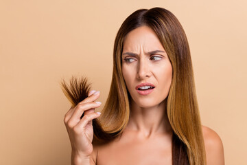 Photo of unhappy age brown hair lady look split ends without outfit isolated over beige color background