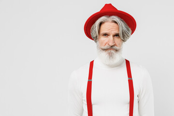 Elderly serious calm fashionable trendy gray-haired mustache bearded man 50s in turtleneck red hat suspenders look camera isolated on plain white background studio portrait. People lifestyle concept.