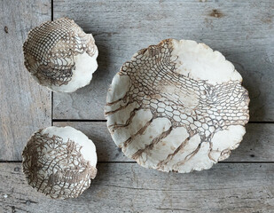 Modern ceramic wall plates with lace pattern on a wooden board