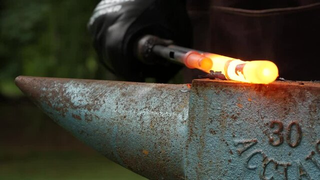Blacksmith pounding on gun barrel