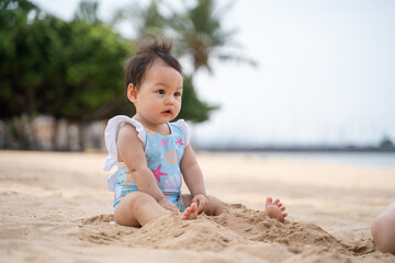 baby infant playing in the sea water and waves on sand beach in morning sunny day. 9 months old baby activity outdoor beach vacation.