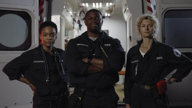 Multiracial team of paramedics standing near ambulance