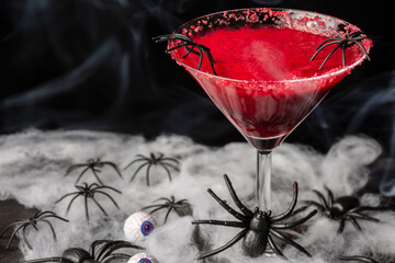 Top view of cherry cocktail for Halloween with spiders, on table with spiders and eyes, selective focus, black background, horizontal