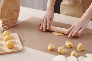 Obraz na płótnie Canvas Close-up image of woman rolling out piece of dough when making mooncakes at home