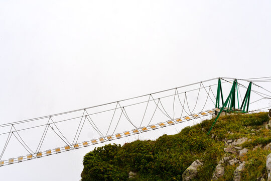 Fototapeta The empty rope bridge over the cliff on foggy day