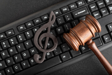 Protection of music as intellectual property. Treble clef on the keyboard next to the wooden gavel...