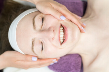 Modeling facial massage in spa salon. Young woman is massaged face for toned skin. Procedure for youth and beauty