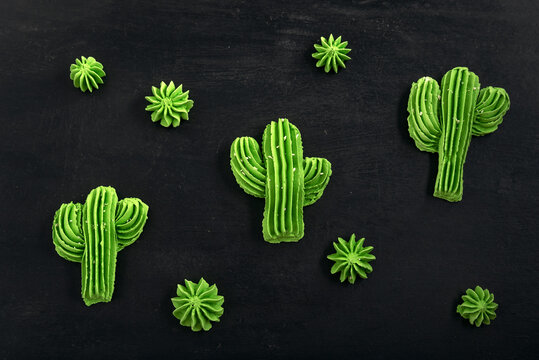 Green air cookies in the form of cactus. French dessert meringe on black table.