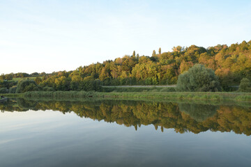 Fototapeta na wymiar Canal de la Sarre en Moselle, l'automne se dessine à petit pas et les couleurs automnales des arbres se reflètent dans l'eau du canal