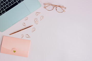 Woman working items with computer, pink envelope, glasses and clips on pink background.