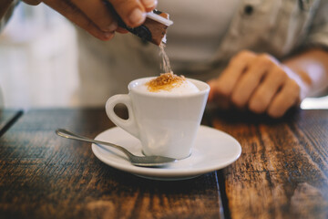 Close up hands putting white sugar in an italian espresso coffee at the bar or restaurant ona...