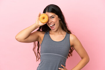 Young caucasian woman isolated on pink background holding donuts in eyes