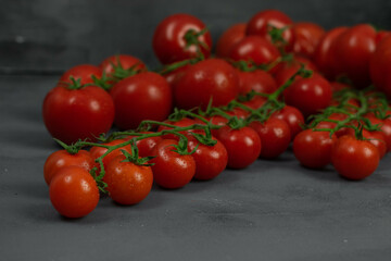 A group of different tomatoes on the vine on grey stone background. Concept for healthy nutrition. Symbolic image. Copy space.
