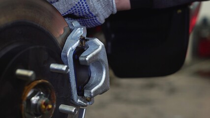 Fototapeta na wymiar The car mechanic unscrews the brake pads. Close-up
