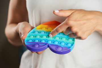 A girl is pressing down with her single finger on the bumps of the toy 