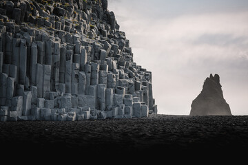 Mount Reynisfjall with basalt columns over the sea water surface in southern Iceland