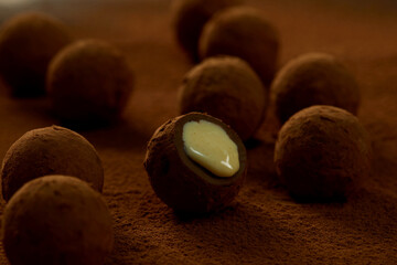 Truffles with cocoa, coconut and sesame seeds with chocolate with cocoa powder, delicious dessert under dramatic lighting