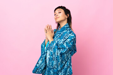 Young woman wearing kimono over isolated blue background scheming something