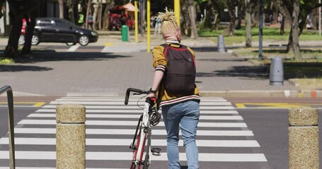 Albino african american man with dreadlocks crossing street with bike - Powered by Adobe