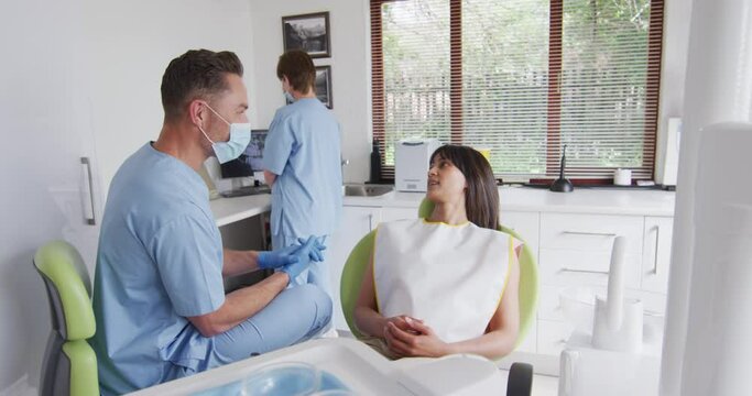 Caucasian male dentist with face mask preparing smiling female patient at modern dental clinic