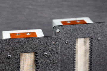 Flat foil ribbon tweeters presented against a gray background. Photo taken under artificial light