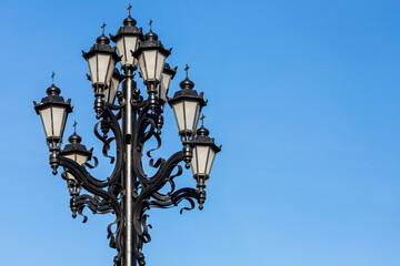 Beautiful vintage lamp post with swirls and curls against sky. Decoration of streets and parks. Illumination of streets in cities and towns