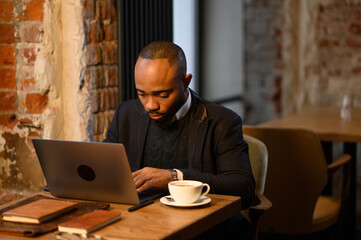 An African American student works at a laptop in a cafe