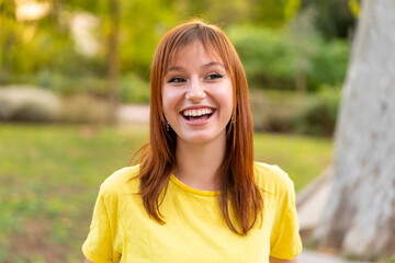 Young pretty redhead woman at outdoors With happy expression