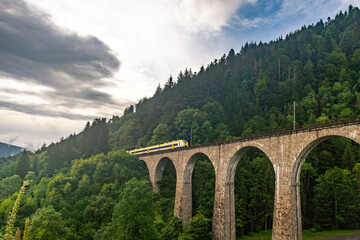 Fototapeta na wymiar Historic railway bridge with a yellow train at the Ravenna Gorge Black Forest