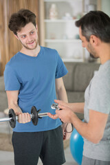 Fototapeta na wymiar personal trainer with stopwatch training young lad with weights