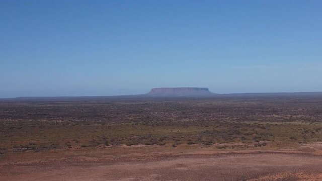 an aerial descending clip of the central australian desert with mt conner in the distance at the northern territory of australia