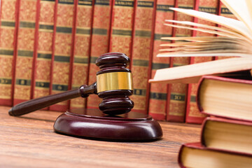 Law concept - Open law book with a wooden judges gavel on table in a courtroom or law enforcement...