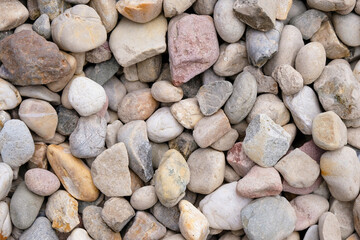 Fototapeta premium Colorful pebbles background. Pink, gray, beige, orange stones for design.