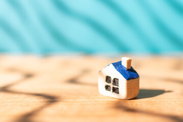 One miniature toy house on a wooden table.Yellow house model blurred blue background.Copy space.Closeup.
