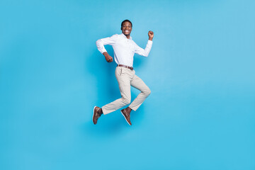 Fototapeta na wymiar Photo of lucky pretty dark skin guy dressed formal shirt humping high rising fist smiling isolated blue color background