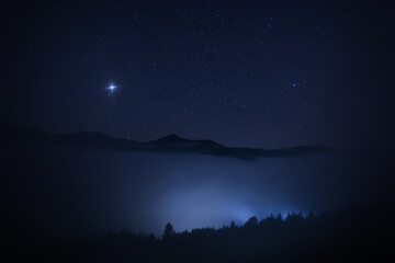 Beautiful view of misty mountains under starry sky at night