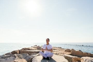young asian woman meditates with her hands together as if praying sitting by the sea, concept of spirituality and relax
