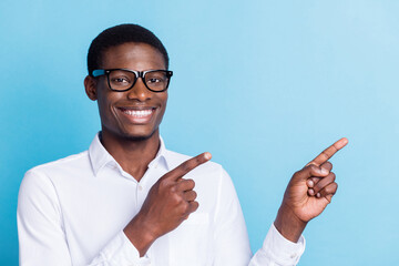 Photo of cute charming dark skin guy dressed formal shirt glasses smiling pointing empty space...