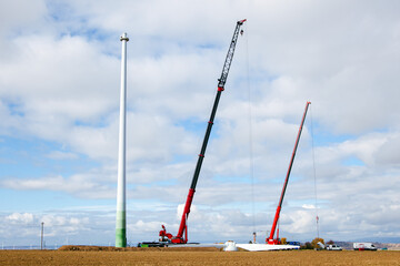 Deinstallation of old wind turbine. Blades of a wind generator lying on the ground and cranes. Tower of a wind-generating facility. Farmland with construction work at the wind farm. Wörrstadt, Germany