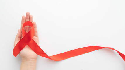 World AIDS day in December month campaign. Human hands holding red ribbon awareness on white...