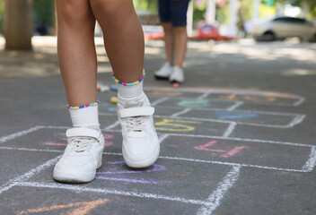 Fototapeta premium Little children playing hopscotch drawn with chalk on asphalt outdoors, closeup