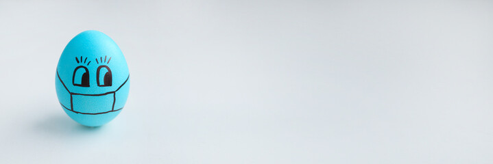 Blue Easter egg in a protective medical mask. Easter quarantine.