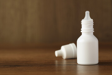 Fototapeta na wymiar Bottle of nasal spray and cap on wooden table, space for text