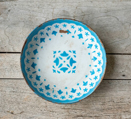 Vintage enameled metal plate with geometrical pattern - on a rustic wooden table