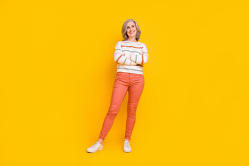 Photo of confident pretty lady pensioner wear striped pullover arms crossed looking empty space smiling isolated yellow color background