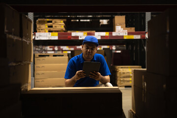 Young worker in blue uniform checklist manage parcel box product in warehouse. Asian man employee...