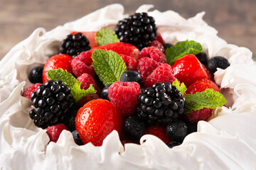Delicious Pavlova cake with meringue topped and fresh berries on wooden table