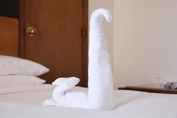 Poster Folded from a white towel swan on the bed in the hotel room. Traditional decoration of the rooms of the hotel guests when cleaning the rooms. © Galina