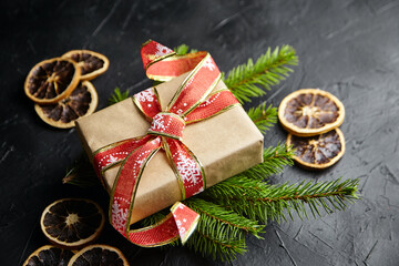 Christmas gift box and fir tree branches with dried orange fruit on black background